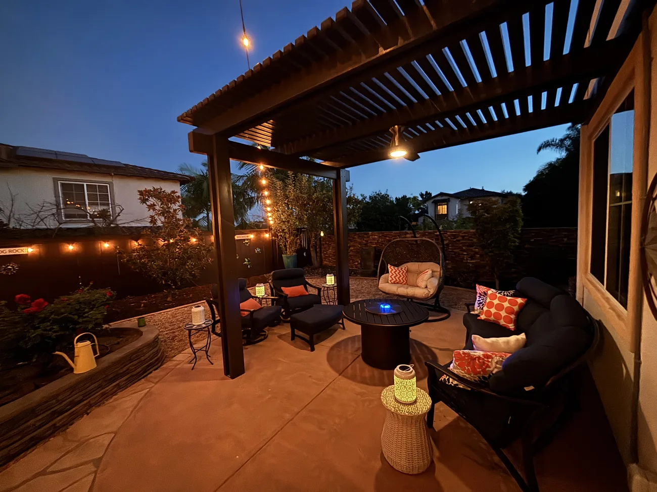 Twilight view of the covered backyard patio and pergola at 2193 Vista La Nisa, lit with string lights in the evening