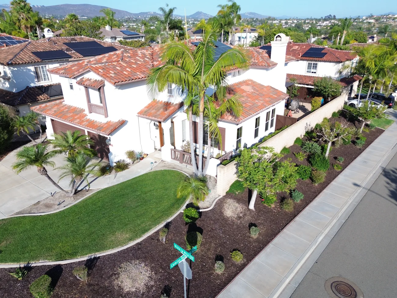 Golden-hour aerial view of the front yard, circular lawn, and palm-lined entry at 2193 Vista La Nisa